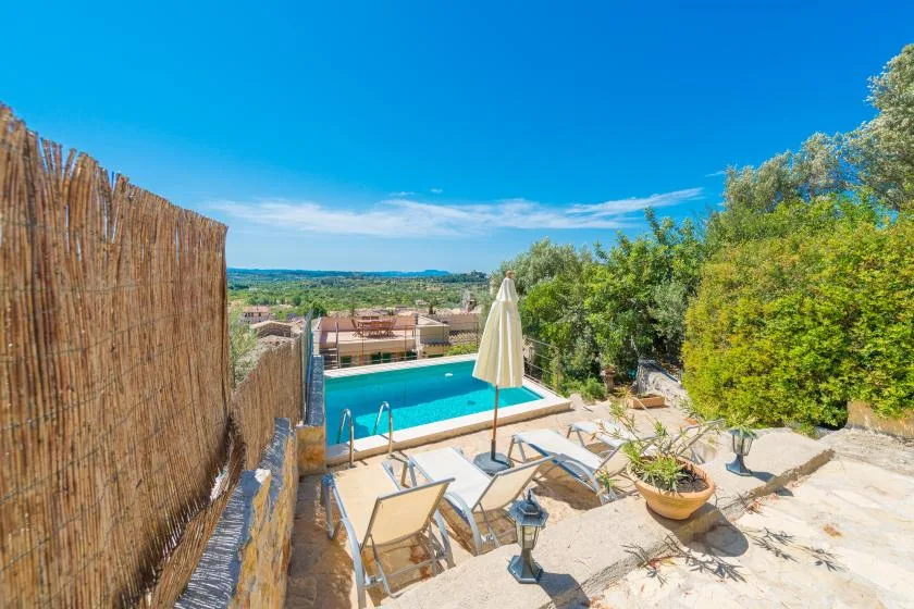 Outdoor pool area with loungers and a closed umbrella beside the water.