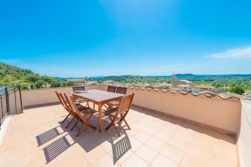 A sunny rooftop terrace with outdoor seating and a view over the surrounding town.