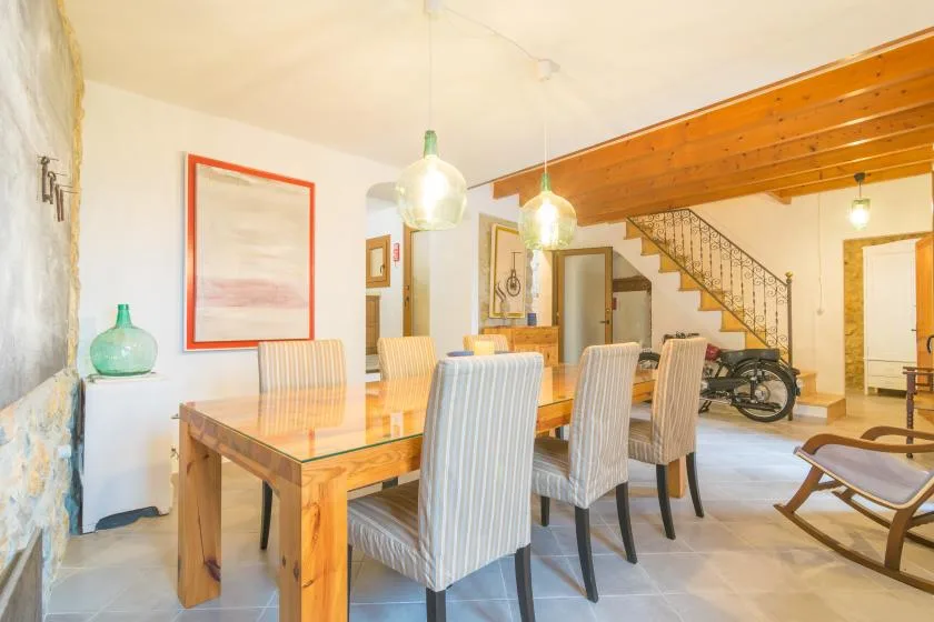 A dining area with a wooden table and upholstered seating beneath pendant lights.