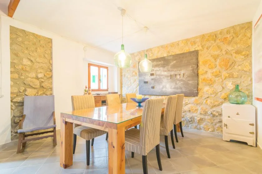 A dining area with a wooden table and chairs beside stone walls.