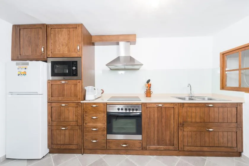 A kitchen with wooden cabinets, a refrigerator, and a built-in oven.