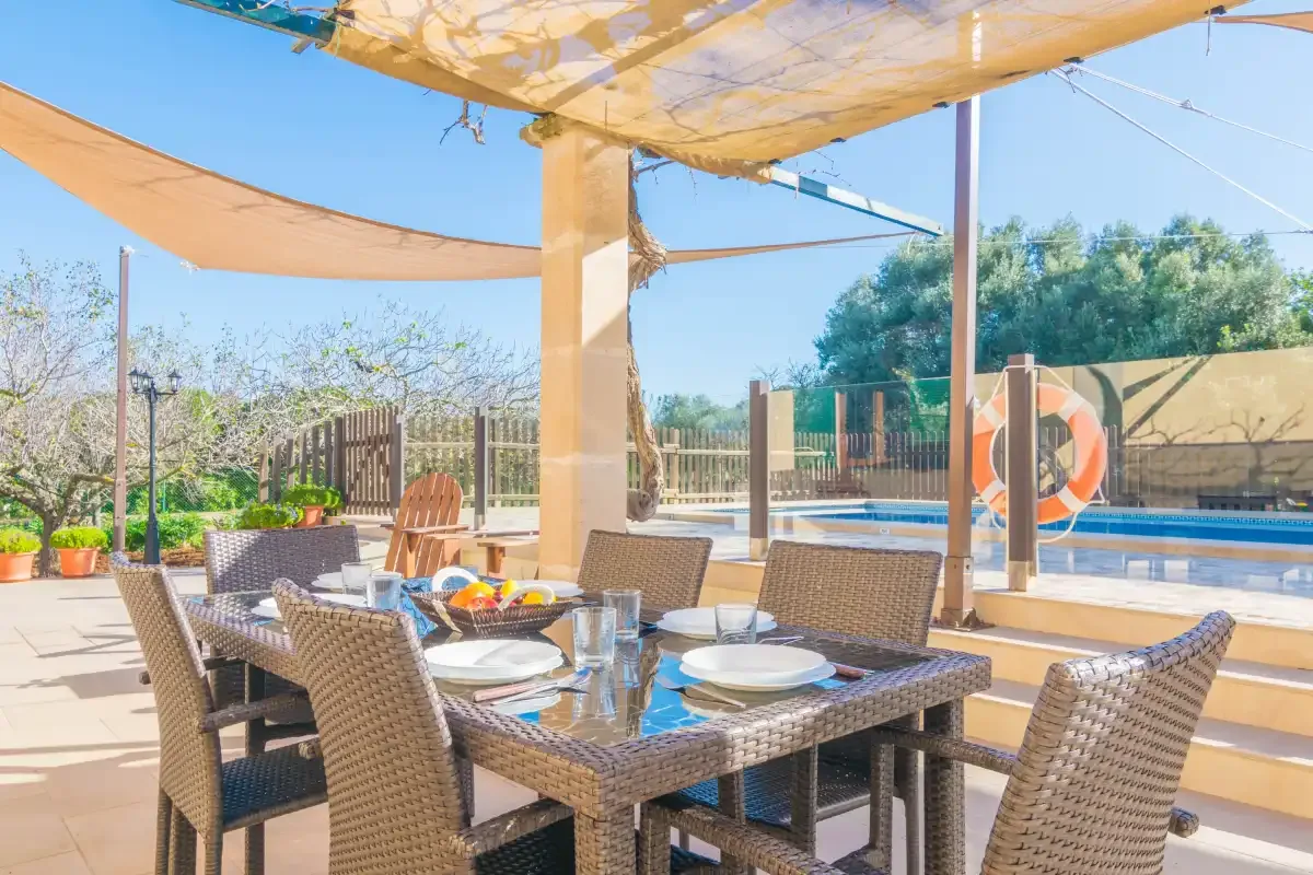 A shaded outdoor dining area beside a swimming pool.
