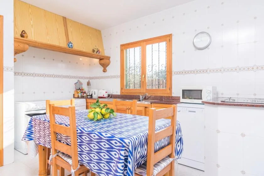 A kitchen dining area with a patterned tablecloth and wooden cabinets.