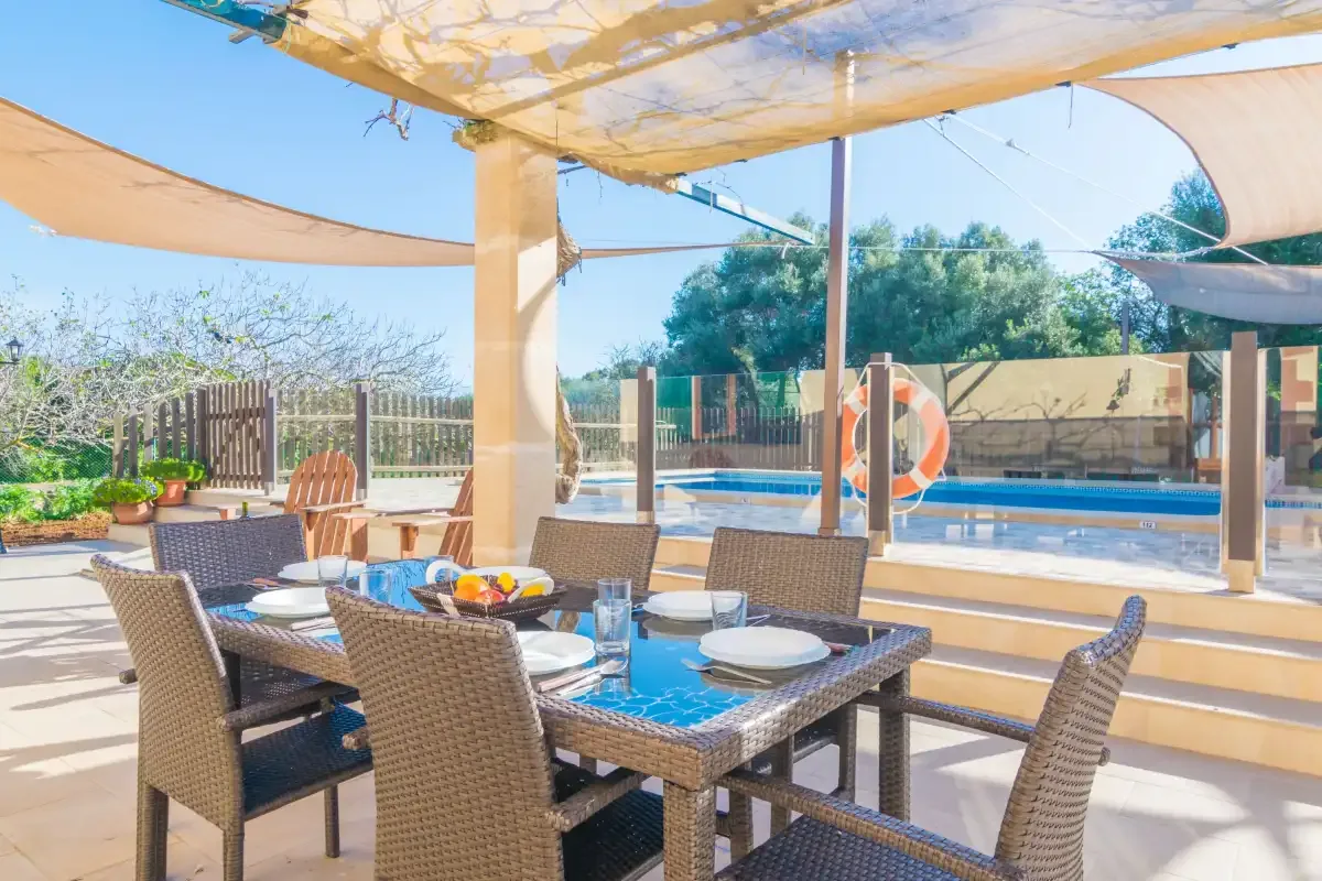 An outdoor dining area with woven seating overlooks a swimming pool.