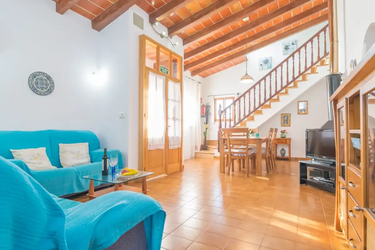 A living and dining area with turquoise seating, a wooden table, and a staircase.