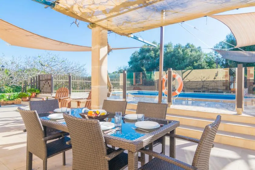 An outdoor dining area with a table and seating beside a swimming pool.