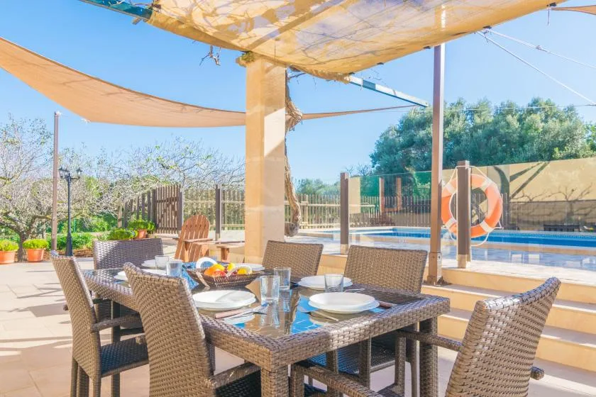 A shaded outdoor dining area with a table set beside a swimming pool.