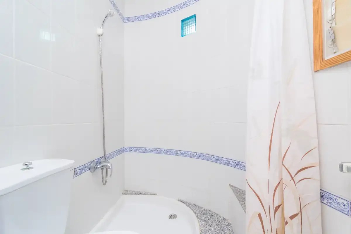A tiled bathroom with a bathtub, shower, and patterned curtain.