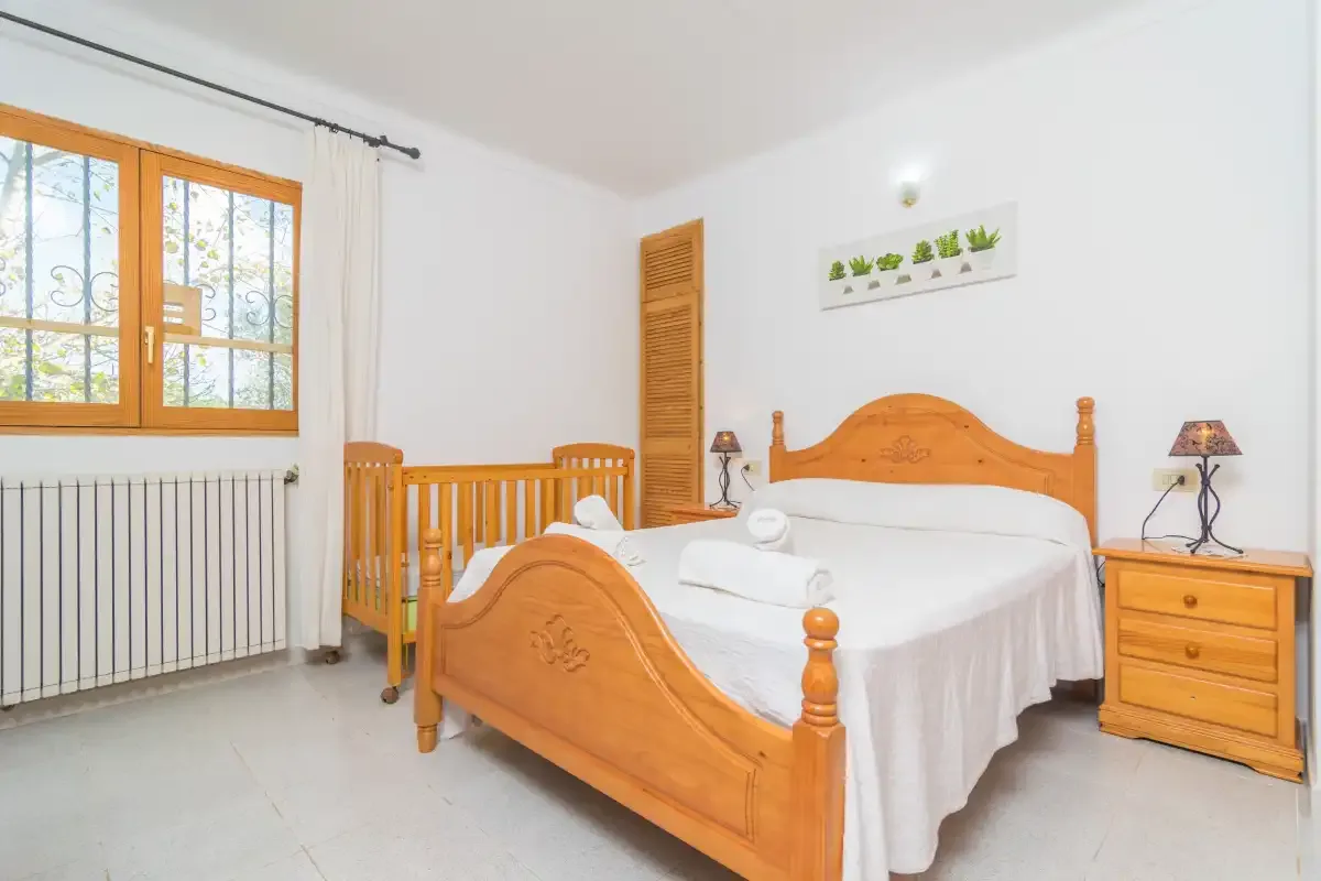 A bright bedroom with a wooden bed and a window.
