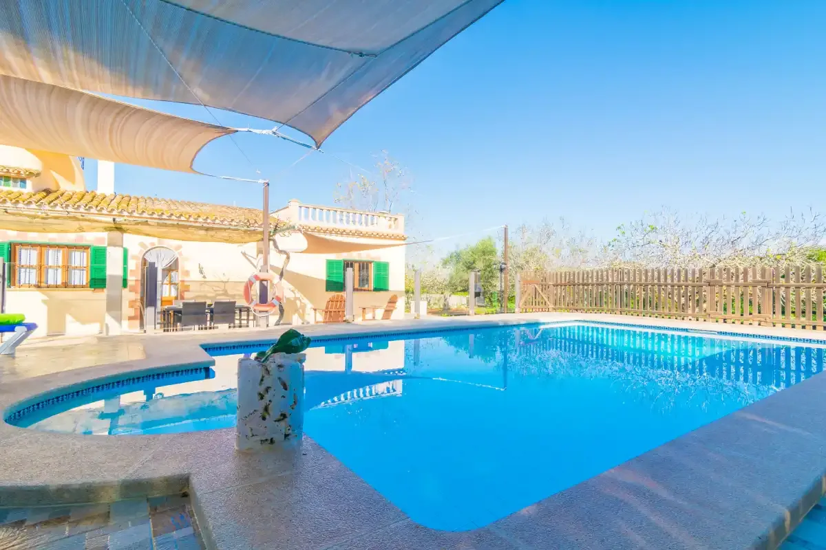A swimming pool beside a house, shaded by a large canopy.