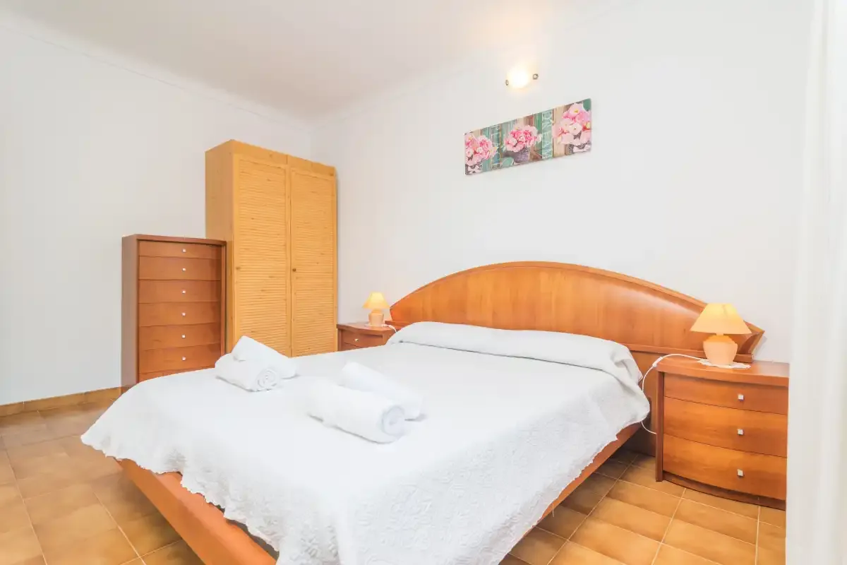 A bedroom with a wooden bed, bedside tables, and wardrobes.