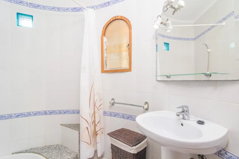 A tiled bathroom with a sink, mirror, and shower curtain.