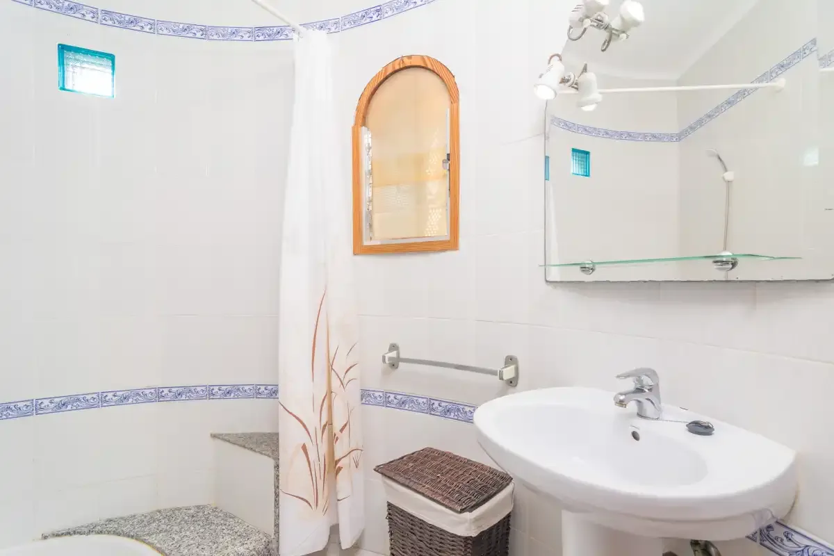 A bathroom with a sink, mirror, and shower curtain.