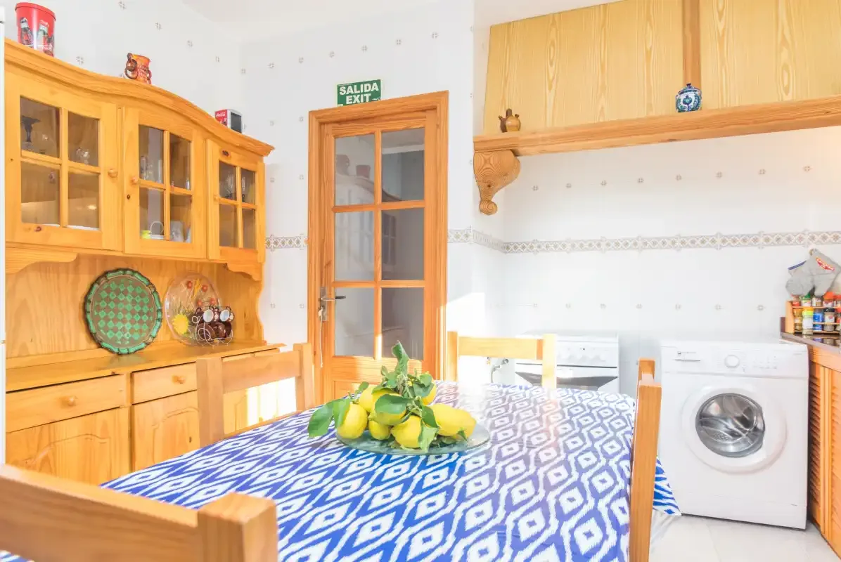 A bright kitchen and dining area with a table covered in a patterned cloth.