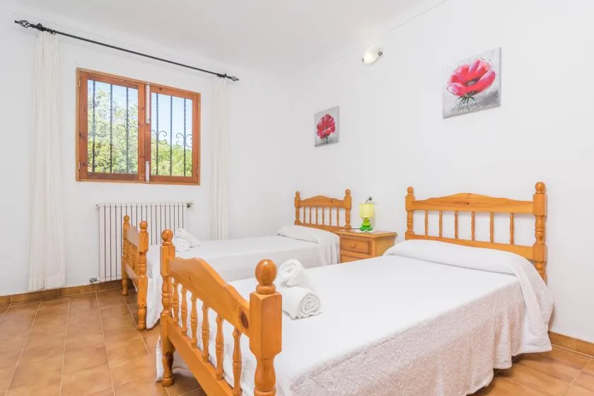 A bright bedroom with two wooden beds and a window.