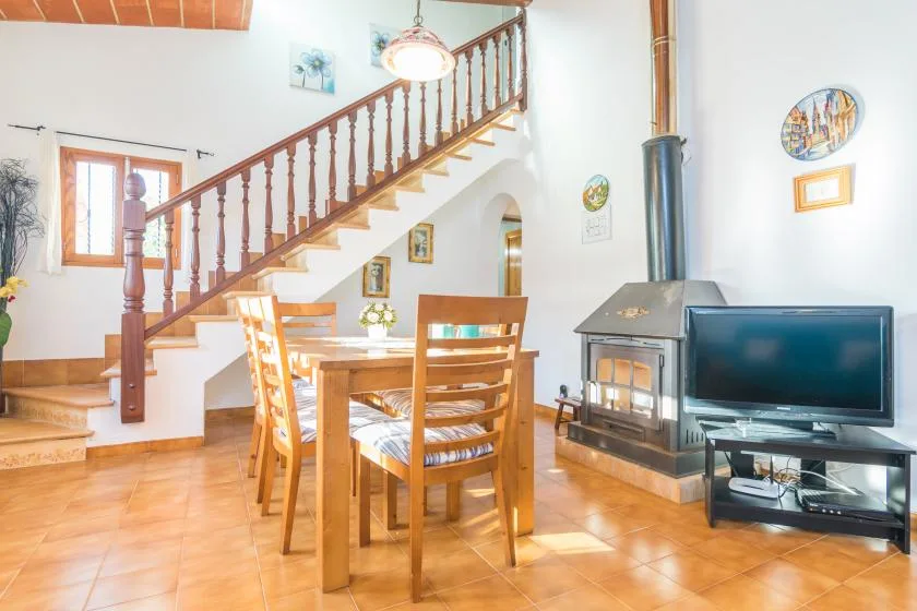 A dining area and living space with a wooden staircase and fireplace.