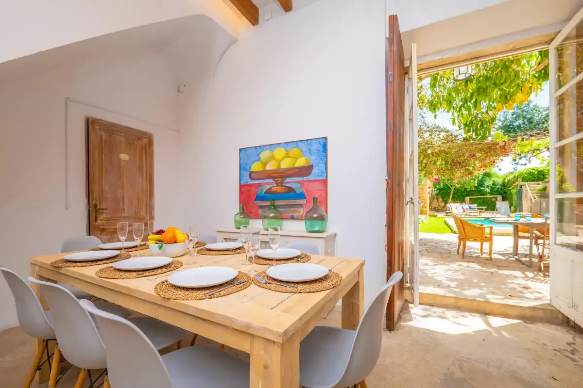 A dining area with a set table beside open doors leading to a garden.