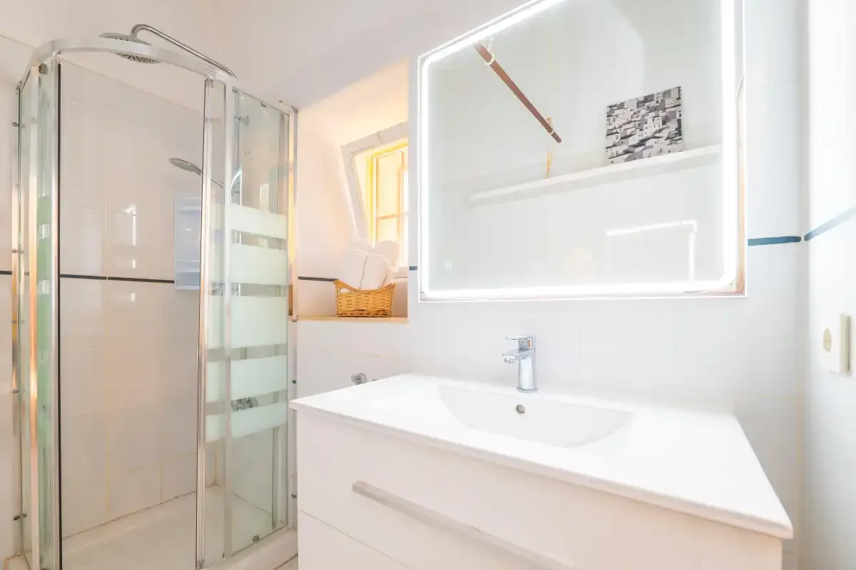 A bright bathroom with a shower and a white sink cabinet.