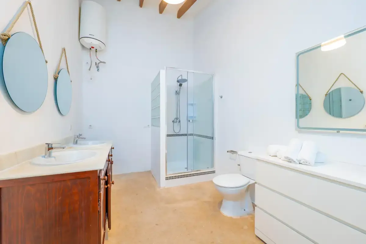 A bright bathroom with a glass shower, sink, and large mirror.