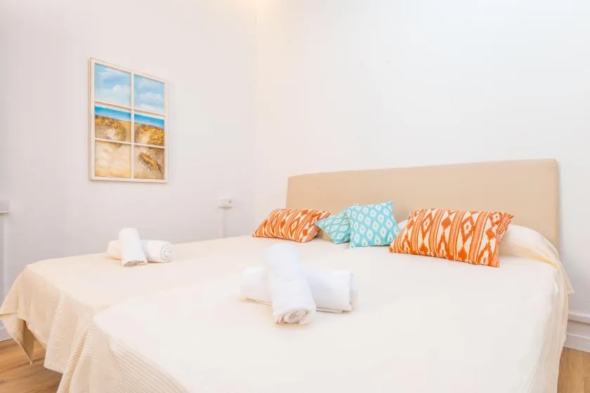 A bright bedroom with a large bed and colorful patterned pillows.
