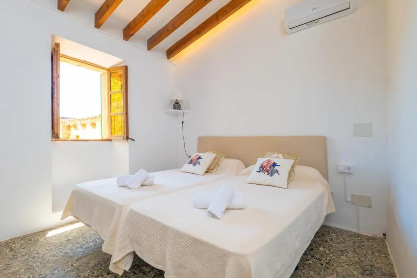 A bedroom with two beds beneath exposed wooden ceiling beams.