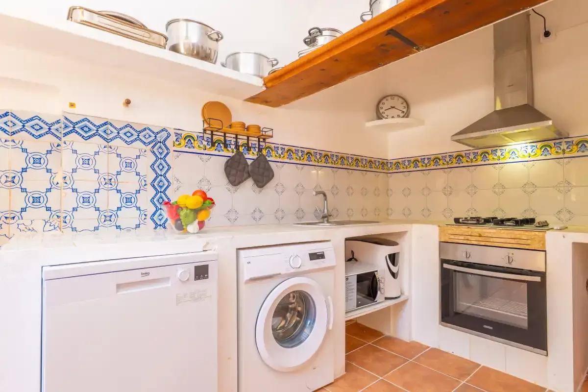 A kitchen with a washing machine, oven, and decorative tile backsplash.