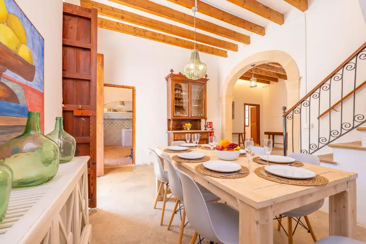 A dining room with a long table and exposed wooden ceiling beams.