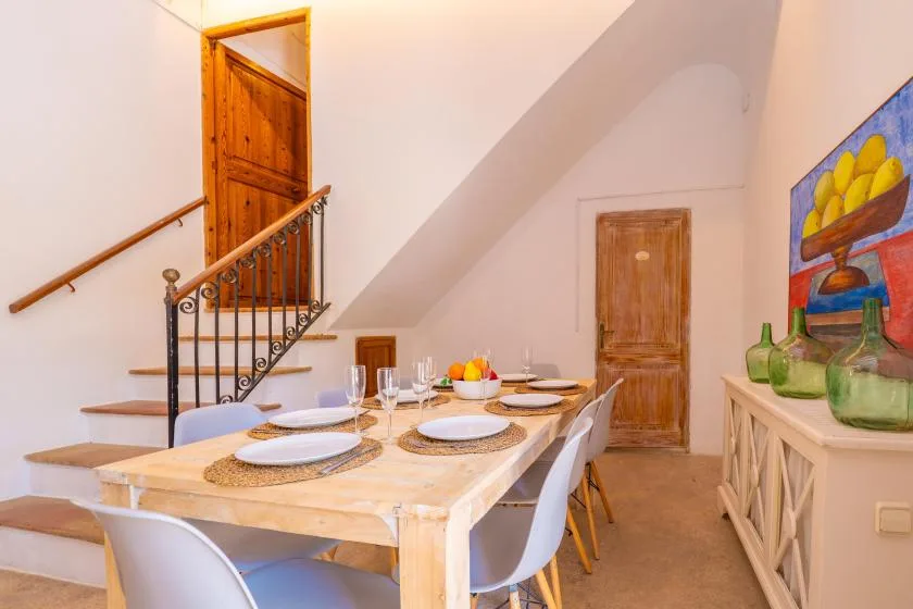 A dining area with a set table beside a staircase and wooden doors.