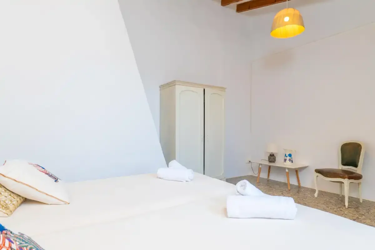 A bright bedroom with a bed, wardrobe, and small desk.