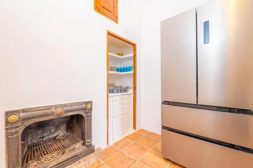 A tiled kitchen with a large refrigerator and a built-in fireplace.
