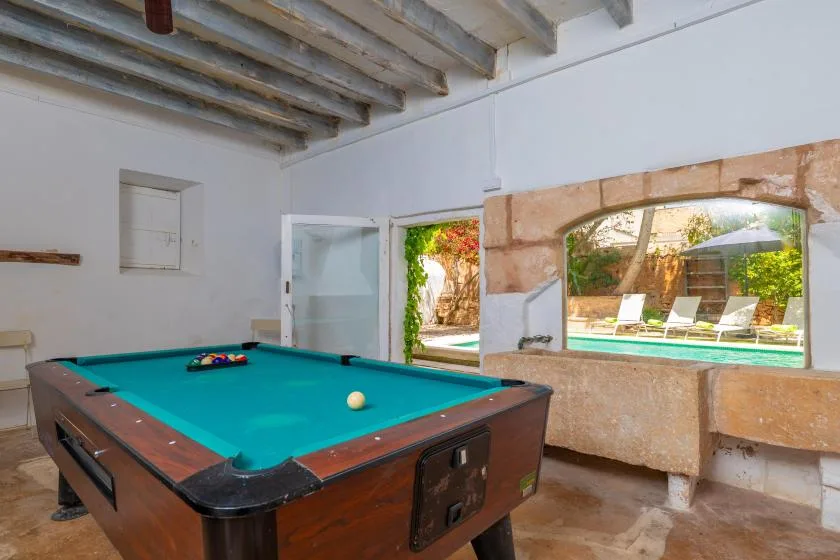 A billiards table fills a bright game room beside open doors to a garden.
