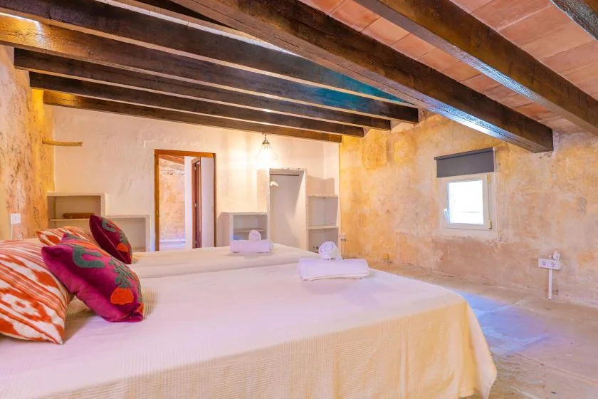 A bedroom with a bed beneath exposed wooden ceiling beams.