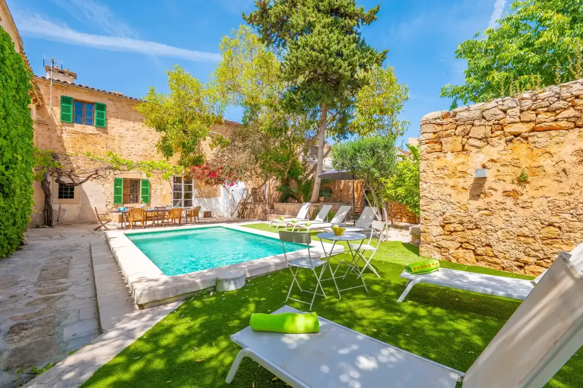 A courtyard with a swimming pool, outdoor seating, and surrounding stone walls.