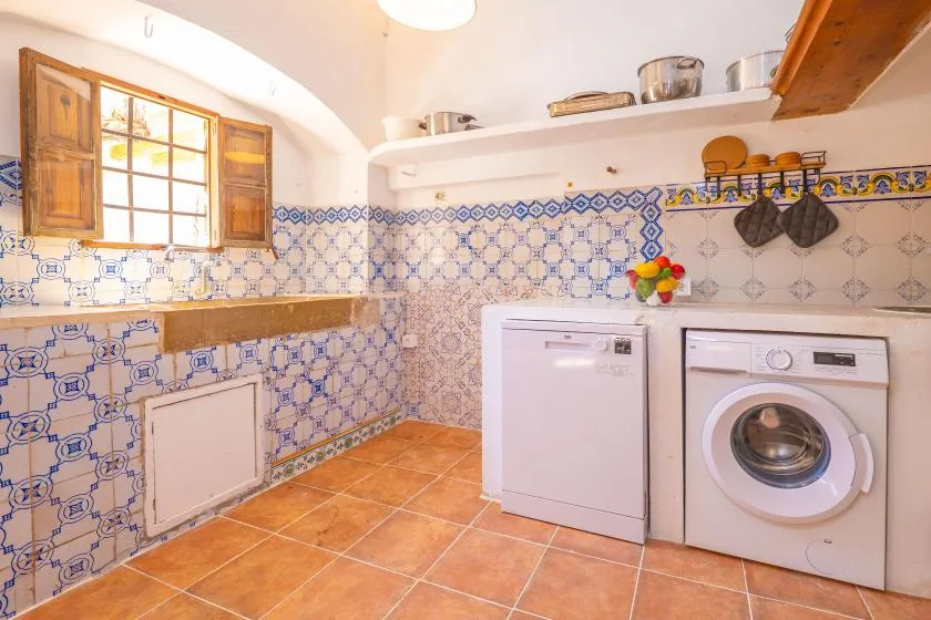A tiled laundry room with a washing machine and a small window.