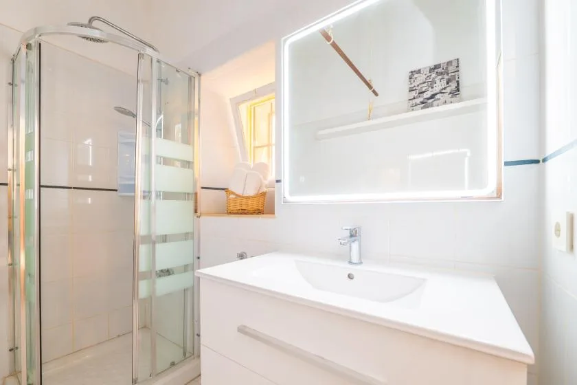 A bright bathroom with a glass shower and a white sink.
