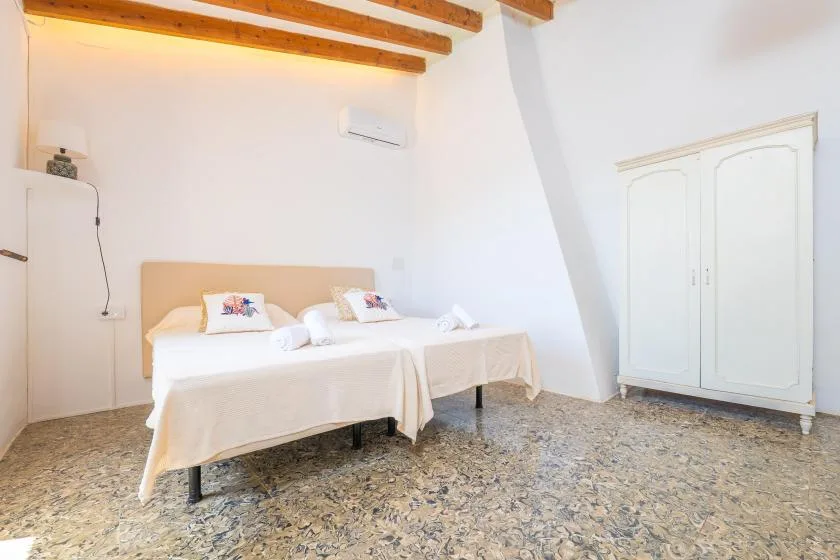 A bedroom with two beds and a white wardrobe.