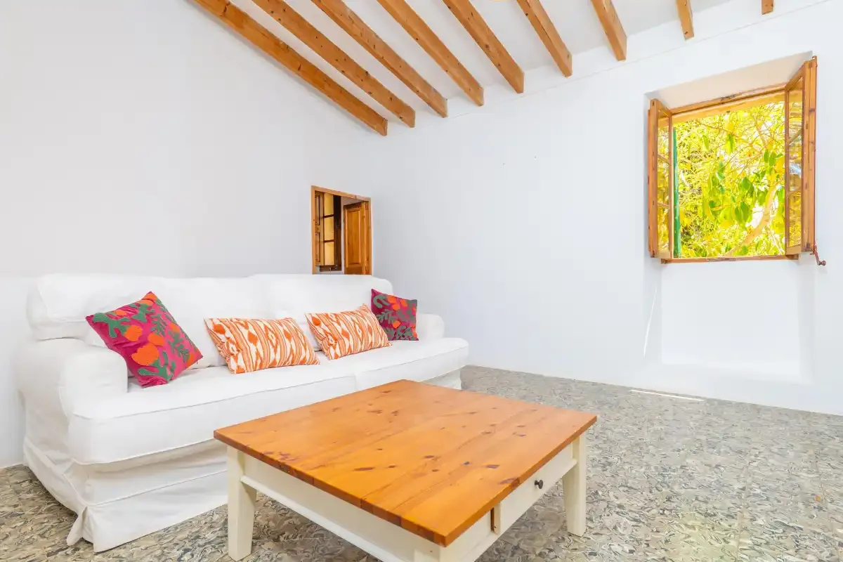 A bright living room with a white sofa and wooden coffee table.