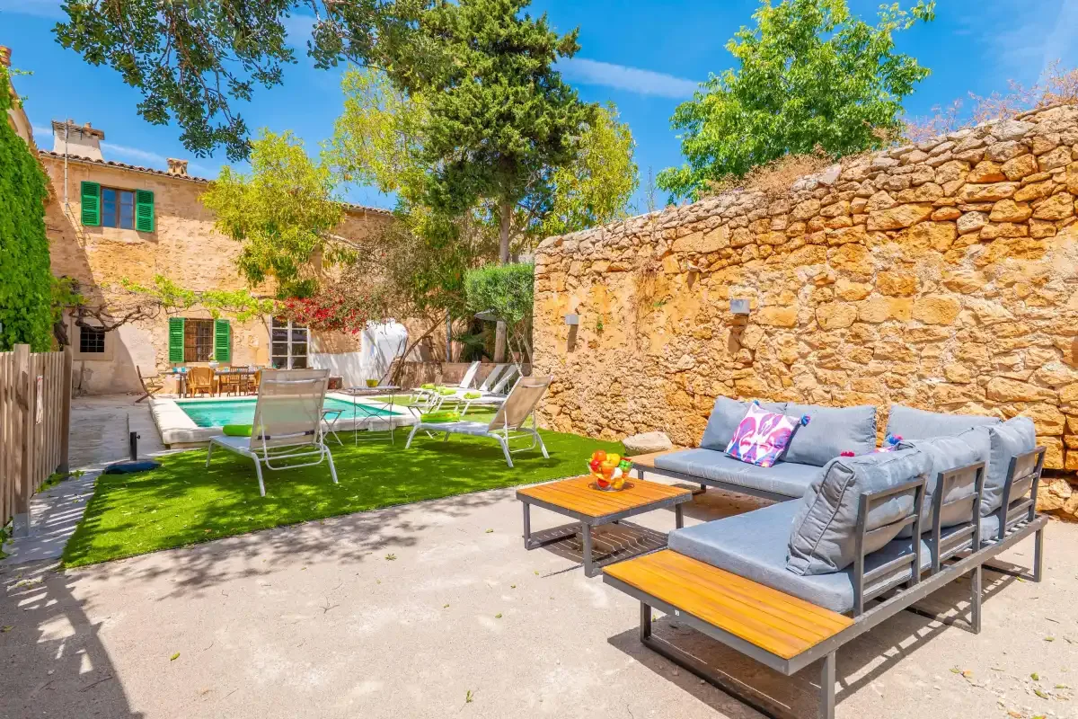 An outdoor patio with seating beside a stone wall and a small pool.
