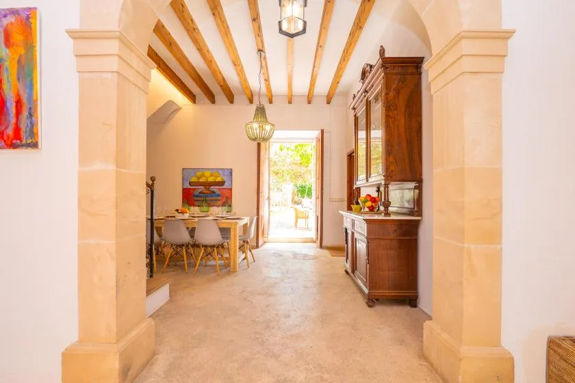 A dining area with a wooden table sits beside a bright open doorway.