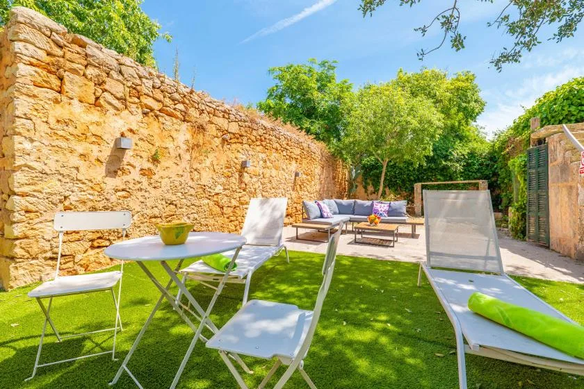 An outdoor patio with lounge seating and a table beside a stone wall.