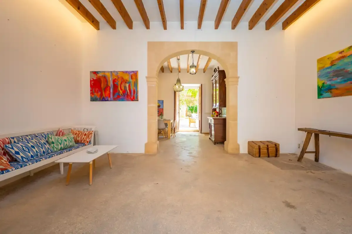 A bright interior room with a central archway, colorful wall art, and seating.