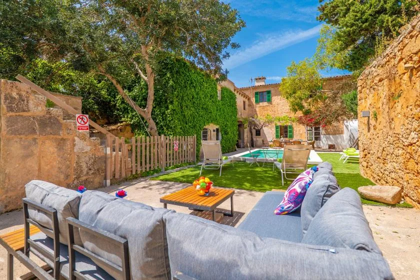 A sunny courtyard patio with outdoor seating, a table, and greenery.