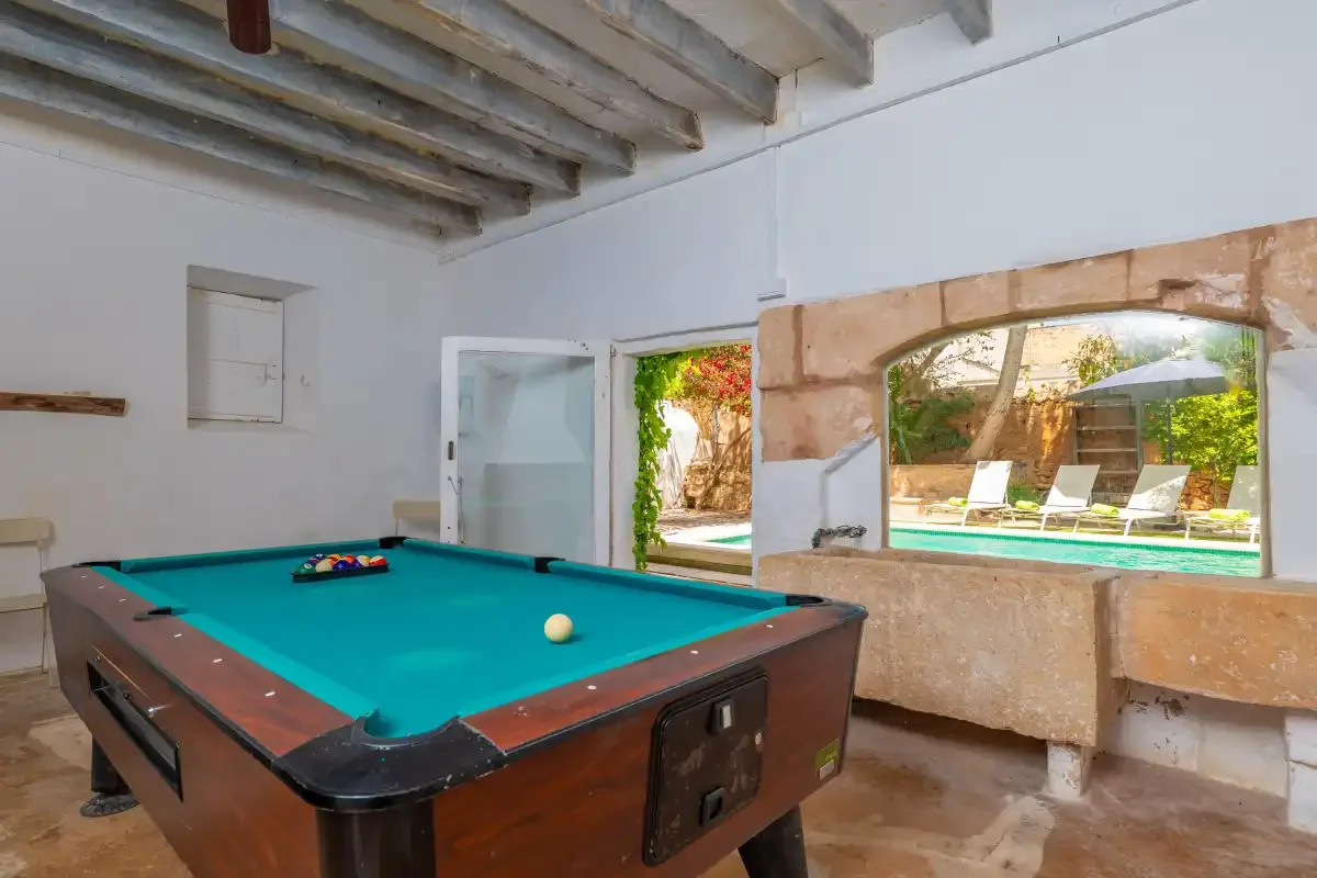 A game room with a pool table beside an open view of the outdoor pool.