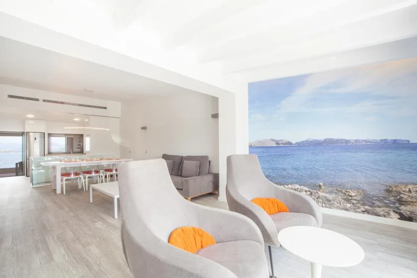 A bright living area opens onto a wide sea view, with seating and a dining area.