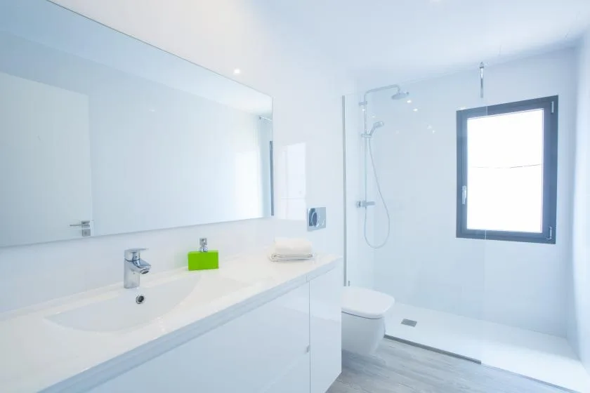 A bright bathroom with a long sink counter and a glass shower area.