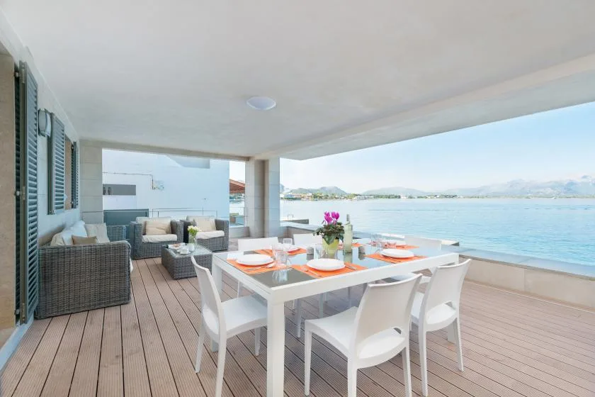 A covered outdoor dining area with a table overlooking the water.