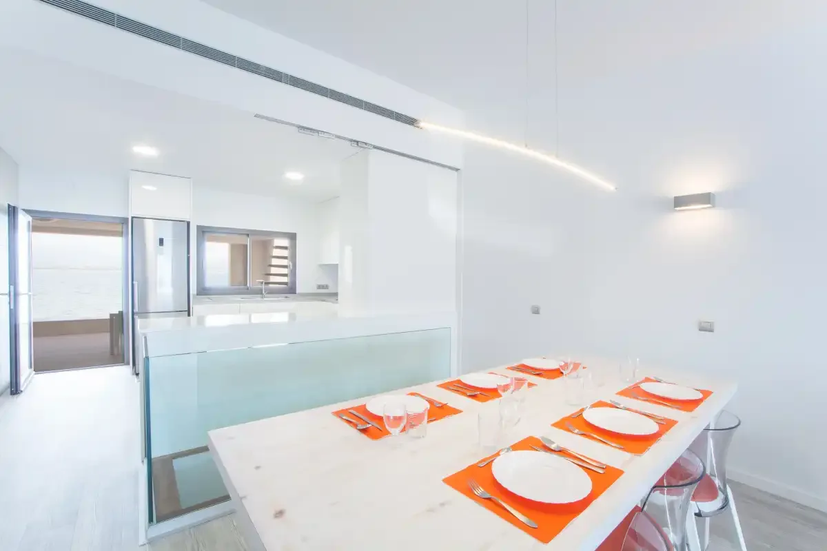 A bright dining area with orange place settings beside a glass partition.