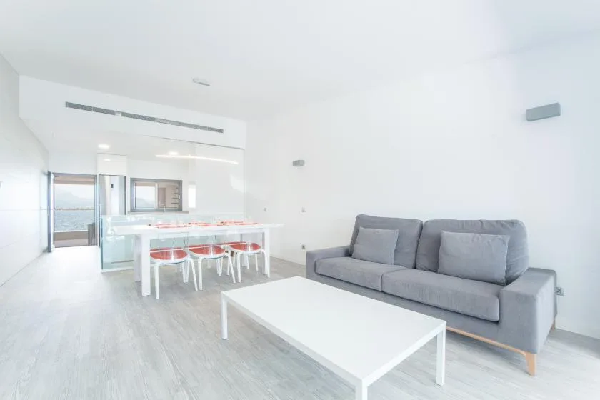 A bright living and dining area with gray seating and a white table.