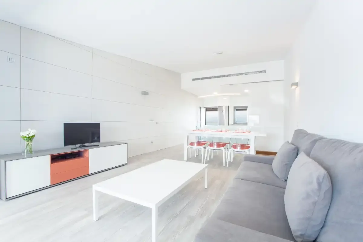 A bright living room with a dining table and gray seating.