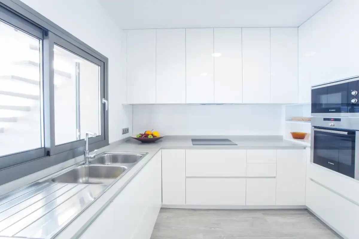 A bright modern kitchen with white cabinets, a countertop, and a sink.